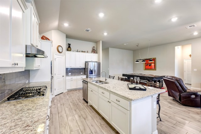 kitchen with decorative backsplash, appliances with stainless steel finishes, white cabinets, and an island with sink