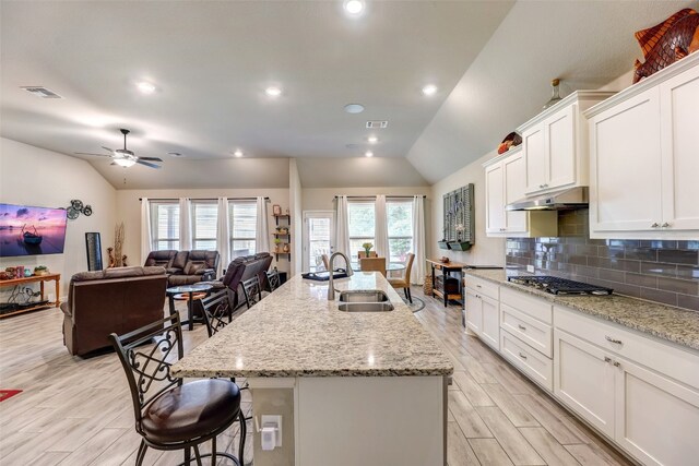 kitchen with a center island with sink, lofted ceiling, sink, and stainless steel gas cooktop