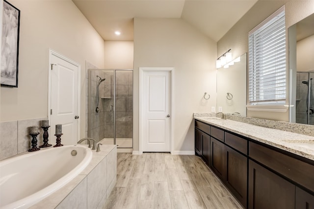 bathroom with vanity, wood-type flooring, shower with separate bathtub, and vaulted ceiling