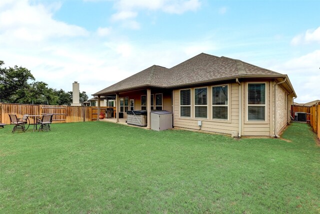 rear view of property with a yard and central air condition unit