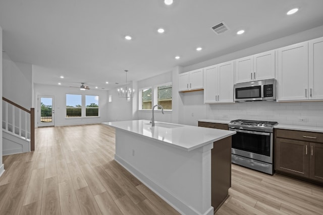 123 Cibolo Creek Loop, Bastrop, TX 78602 - kitchen featuring stainless steel appliances, light countertops, light wood finished floors, a chandelier, and decorative backsplash