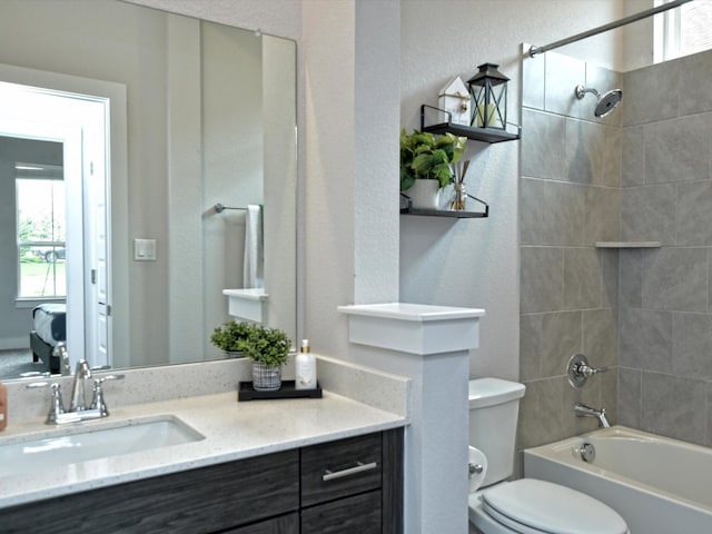 full bathroom featuring tiled shower / bath combo, vanity, and toilet