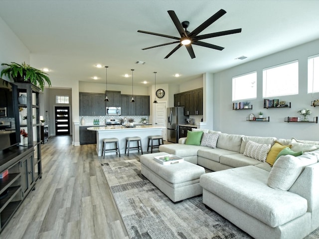 living room featuring ceiling fan and light hardwood / wood-style floors