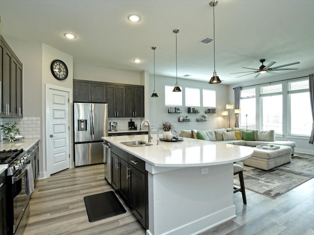 kitchen with sink, light hardwood / wood-style flooring, backsplash, and appliances with stainless steel finishes