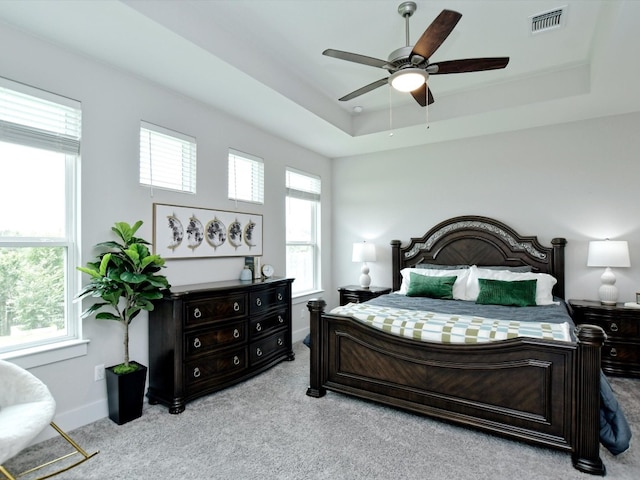 carpeted bedroom with ceiling fan and a tray ceiling