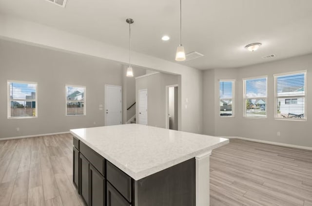 kitchen featuring dark brown cabinetry, a center island, pendant lighting, and light wood-type flooring