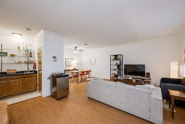 living room featuring ornamental molding, ceiling fan, and light wood-type flooring