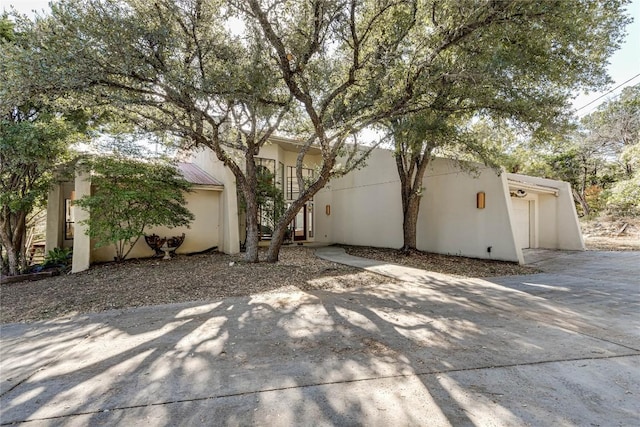 exterior space featuring driveway, an attached garage, and stucco siding