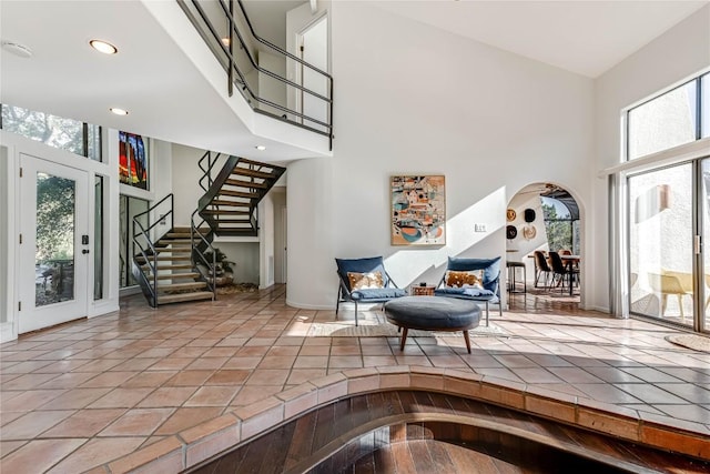 entrance foyer with arched walkways, light tile patterned floors, recessed lighting, a towering ceiling, and stairs