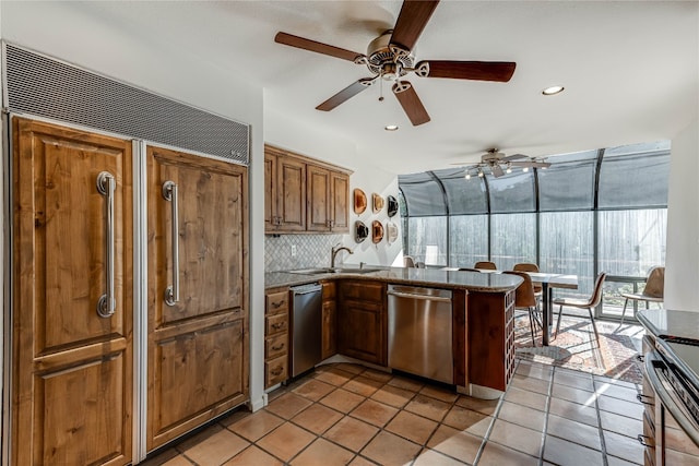 kitchen with kitchen peninsula, tasteful backsplash, stainless steel appliances, sink, and light tile patterned floors