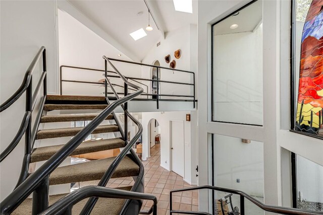 staircase featuring track lighting and lofted ceiling with skylight