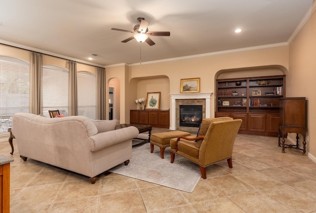 living room with ceiling fan, ornamental molding, and a tile fireplace