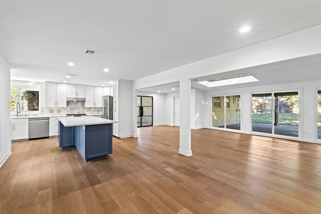 kitchen featuring a breakfast bar, stainless steel appliances, a center island, light hardwood / wood-style floors, and white cabinetry