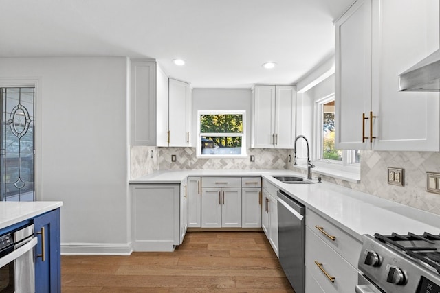 kitchen featuring white cabinets, sink, decorative backsplash, light wood-type flooring, and appliances with stainless steel finishes