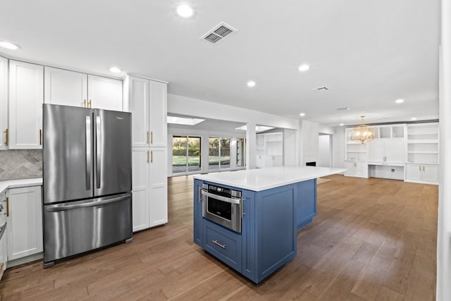 kitchen featuring blue cabinetry, appliances with stainless steel finishes, hardwood / wood-style flooring, and white cabinetry