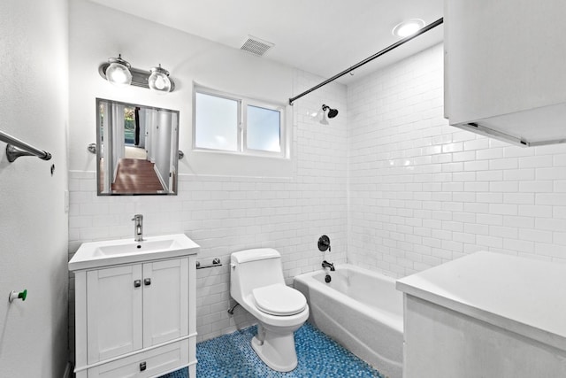 full bathroom with vanity, tile walls, tile patterned flooring, toilet, and tiled shower / bath