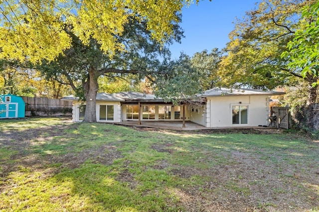 rear view of property featuring a lawn, a storage shed, and a patio