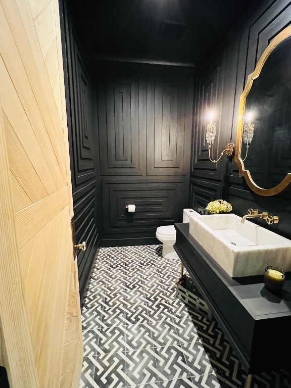 bathroom with vanity, toilet, and wooden walls