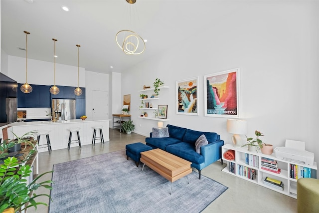 living room featuring a high ceiling, concrete floors, and a notable chandelier