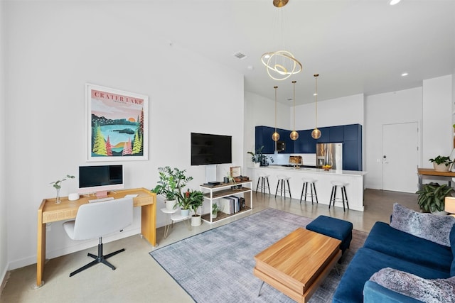 living room featuring a notable chandelier, a towering ceiling, and concrete flooring