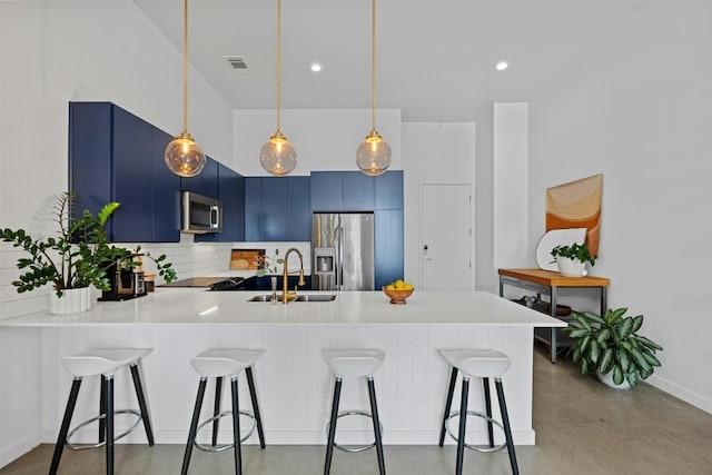 kitchen featuring sink, stainless steel appliances, blue cabinets, kitchen peninsula, and a breakfast bar