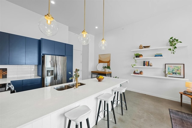 kitchen with kitchen peninsula, stainless steel fridge, a kitchen breakfast bar, sink, and hanging light fixtures