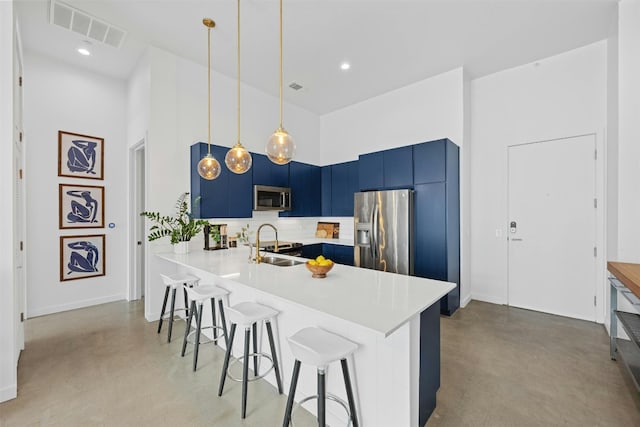 kitchen with blue cabinetry, sink, a towering ceiling, a kitchen bar, and appliances with stainless steel finishes