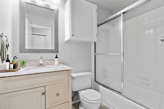 full bathroom featuring combined bath / shower with glass door, vanity, and toilet