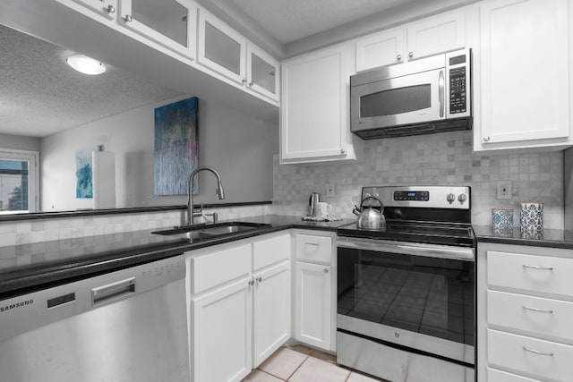 kitchen with white cabinetry, appliances with stainless steel finishes, light tile patterned floors, and backsplash