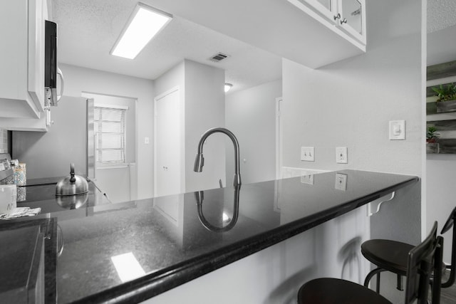 kitchen featuring white cabinets, a breakfast bar area, and kitchen peninsula