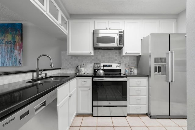 kitchen featuring white cabinetry, tasteful backsplash, light tile patterned floors, stainless steel appliances, and sink