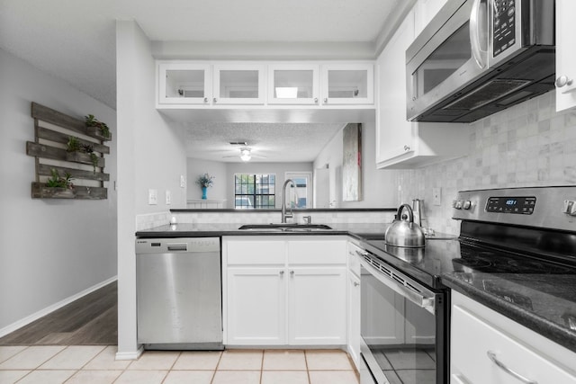 kitchen featuring light tile patterned flooring, sink, white cabinetry, appliances with stainless steel finishes, and ceiling fan