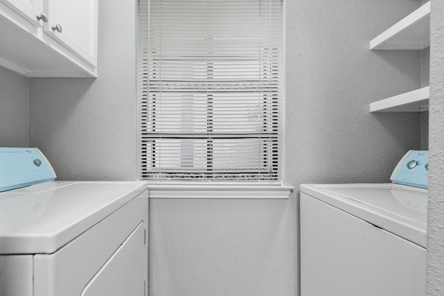 washroom with washer and dryer and cabinets