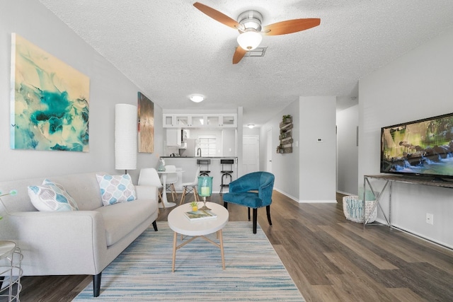 living room featuring wood-type flooring, a textured ceiling, and ceiling fan