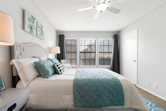 carpeted bedroom with ceiling fan and a textured ceiling