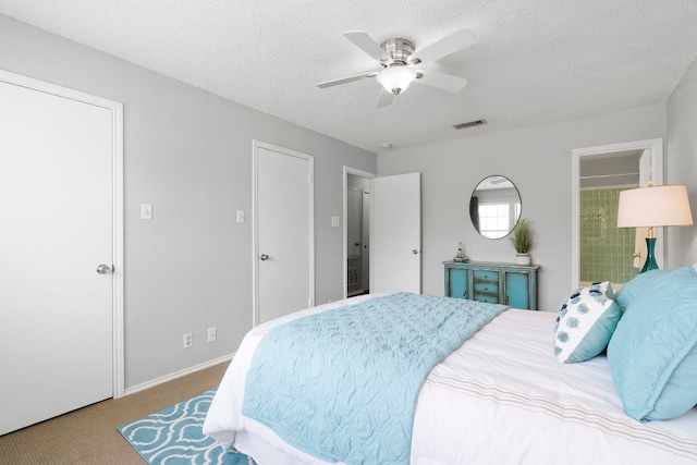 bedroom with light carpet, ceiling fan, ensuite bathroom, and a textured ceiling