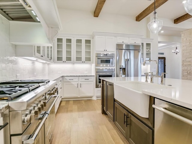 kitchen with sink, tasteful backsplash, pendant lighting, stainless steel appliances, and white cabinets