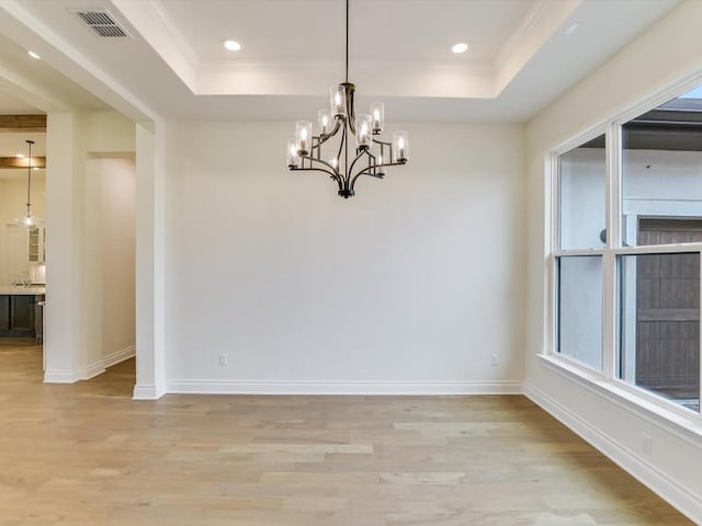 unfurnished dining area featuring a chandelier, light hardwood / wood-style flooring, and a tray ceiling