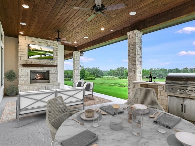 view of patio with an outdoor living space with a fireplace, ceiling fan, area for grilling, and exterior kitchen