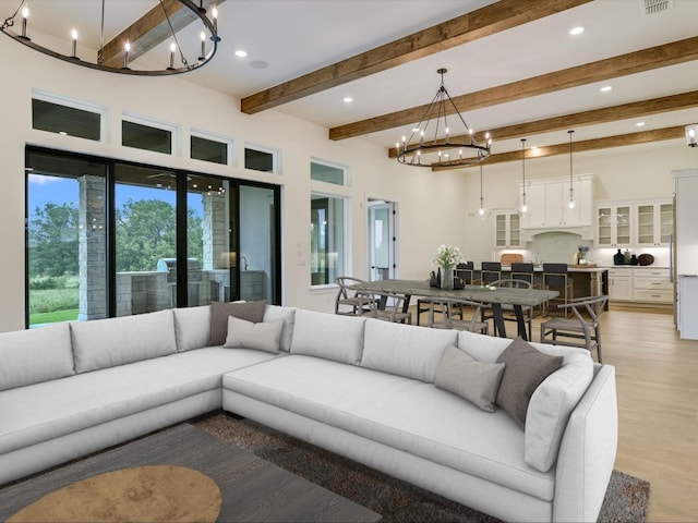 living room with beamed ceiling, light wood-type flooring, and an inviting chandelier