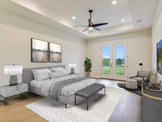 bedroom featuring french doors, ceiling fan, access to exterior, a tray ceiling, and light hardwood / wood-style floors