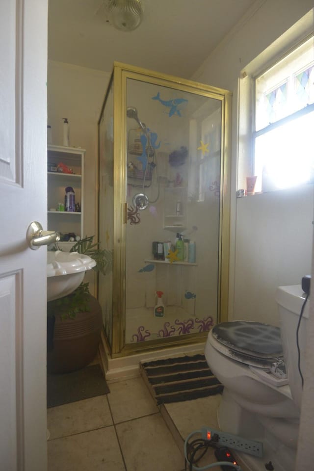 bathroom featuring crown molding, toilet, a shower with shower door, and tile patterned floors