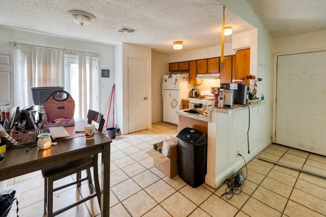 kitchen with light tile floors, white fridge, and a textured ceiling