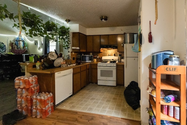 kitchen with white appliances, dark brown cabinets, light hardwood / wood-style floors, tile countertops, and a textured ceiling