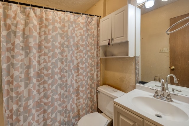 bathroom with a textured ceiling, vanity, and toilet