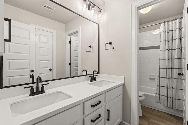 full bathroom with dual vanity, toilet, shower / bathtub combination with curtain, and hardwood / wood-style flooring