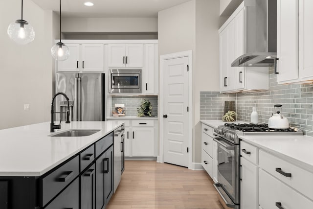 kitchen featuring wall chimney range hood, pendant lighting, decorative backsplash, light wood-type flooring, and premium appliances