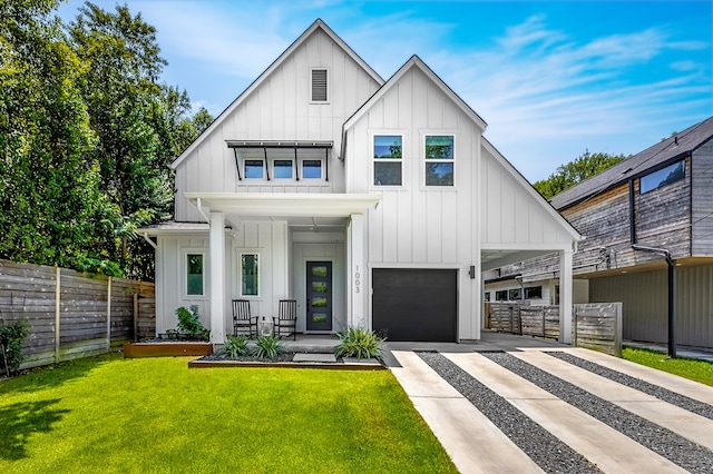 modern farmhouse featuring a garage, a porch, and a front lawn