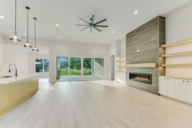 unfurnished living room featuring a wealth of natural light, built in features, a tiled fireplace, and ceiling fan