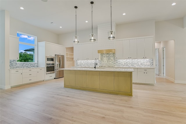 kitchen with appliances with stainless steel finishes, light hardwood / wood-style floors, and a center island with sink